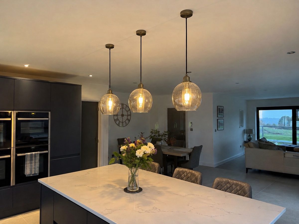 Pendants hung over an island in a dark kitchen, the ceiling intact around them