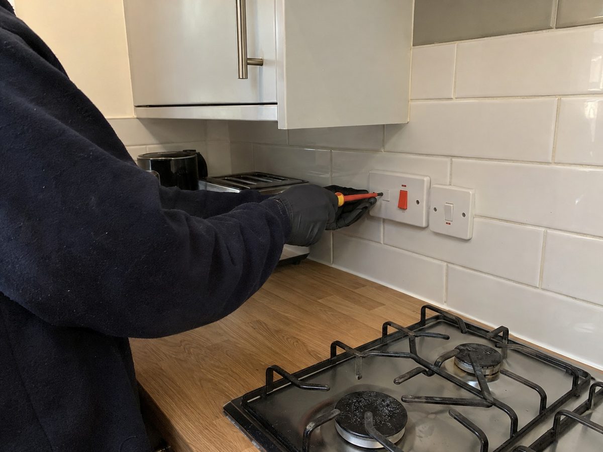 A meter held against a kitchen socket above the worktop