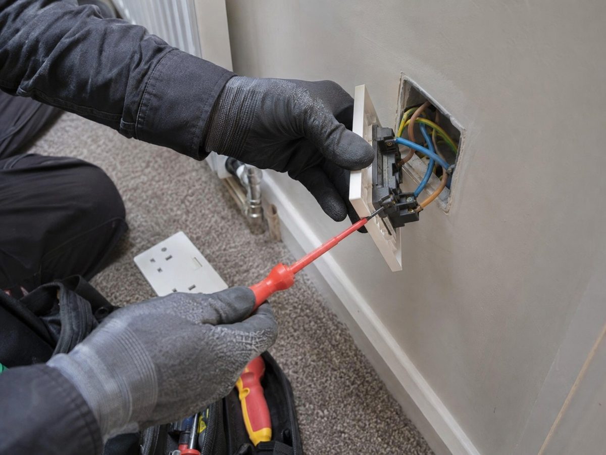 A double socket being wired into a back box in a finished wall